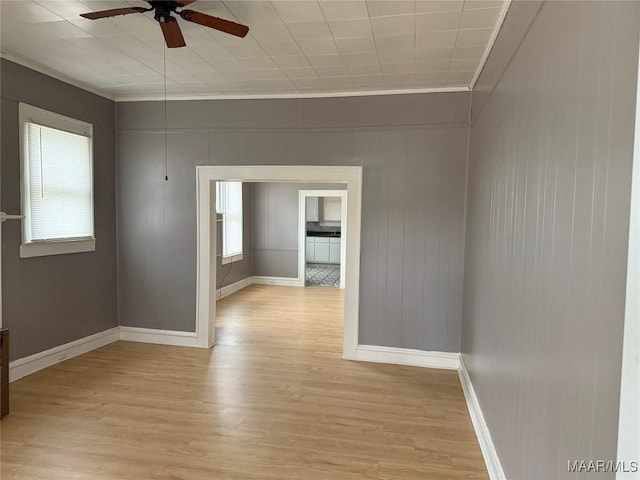 spare room featuring light hardwood / wood-style floors, plenty of natural light, ornamental molding, and ceiling fan