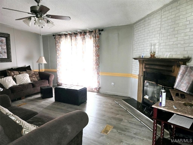 living room featuring a large fireplace, wood-type flooring, and a textured ceiling