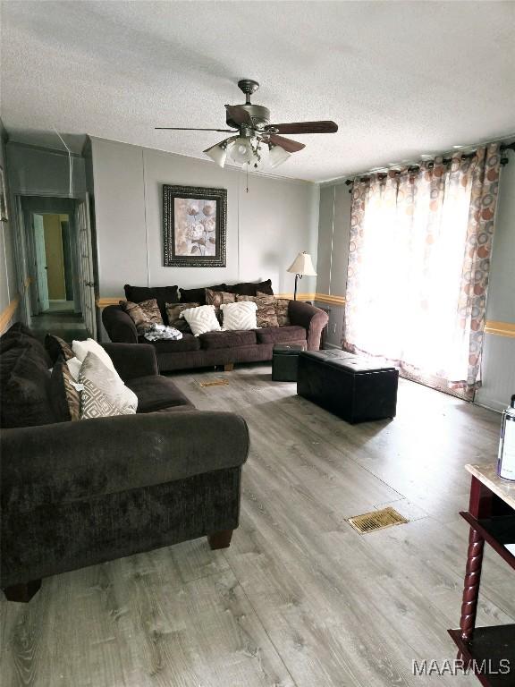 living room featuring ceiling fan, hardwood / wood-style floors, and a textured ceiling