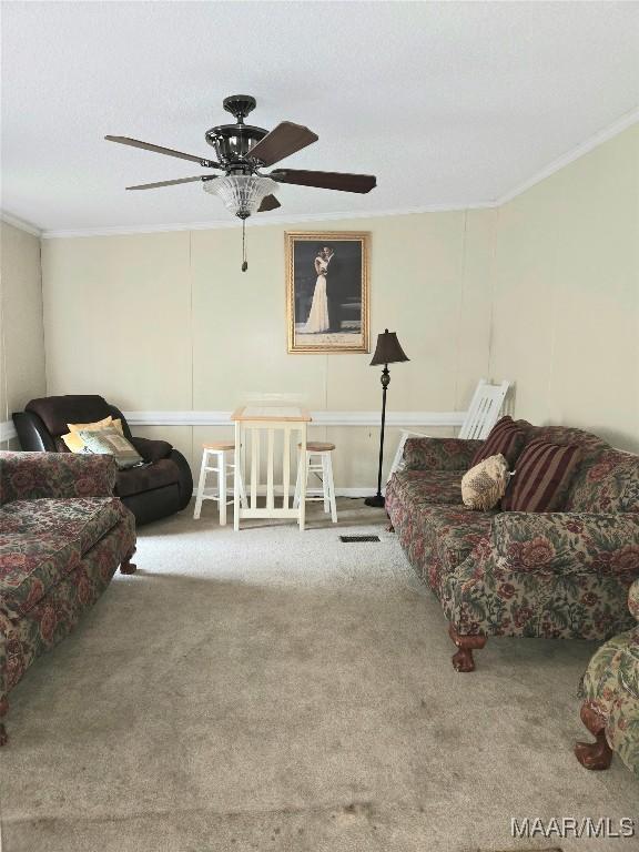 living room with carpet, ceiling fan, and ornamental molding