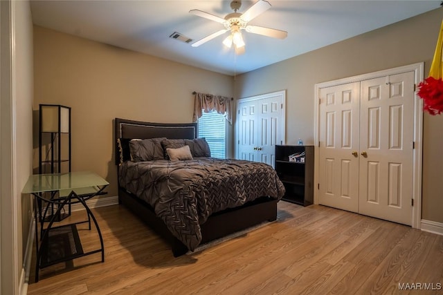 bedroom with multiple closets, ceiling fan, and light wood-type flooring