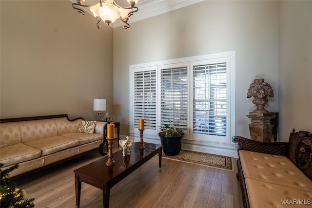 living room with hardwood / wood-style flooring, an inviting chandelier, and ornamental molding