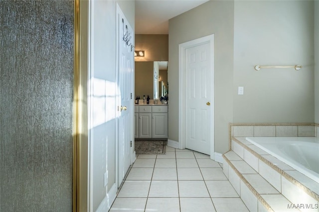 bathroom featuring tile patterned flooring, vanity, and a relaxing tiled tub