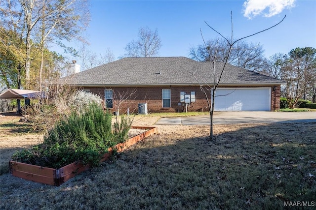 view of front of house featuring a front yard, a garage, and central AC unit