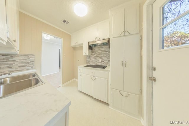 kitchen with exhaust hood, black electric stovetop, sink, ornamental molding, and white cabinetry