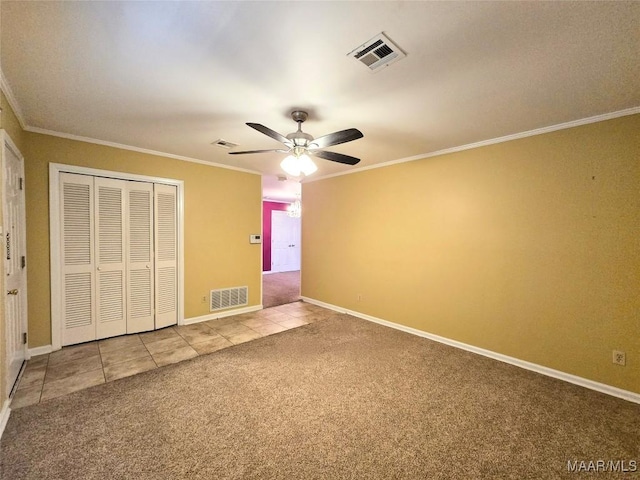 unfurnished bedroom with ceiling fan, carpet floors, crown molding, and a closet