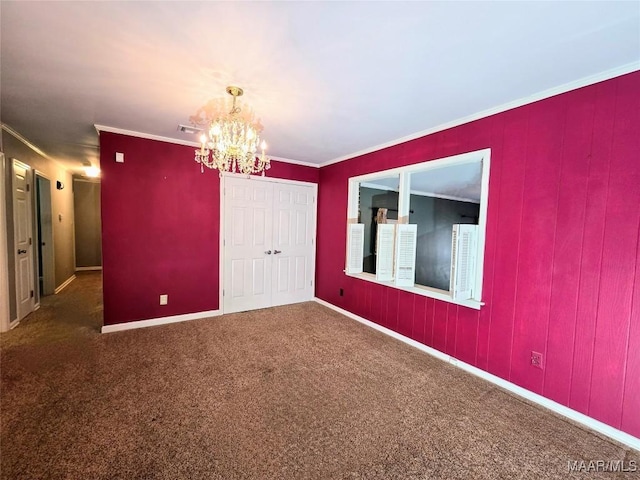 empty room with dark colored carpet, ornamental molding, and a notable chandelier