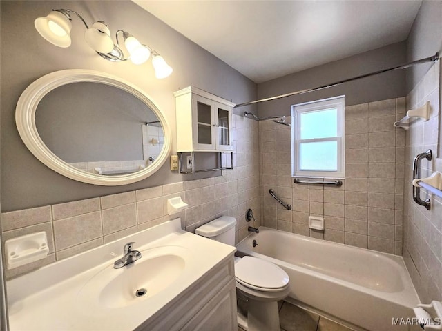 full bathroom with tiled shower / bath combo, toilet, tile walls, and vanity