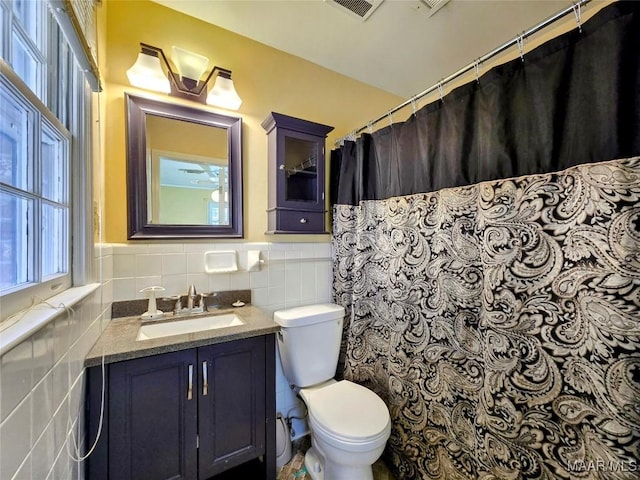 bathroom with vanity, toilet, and tile walls