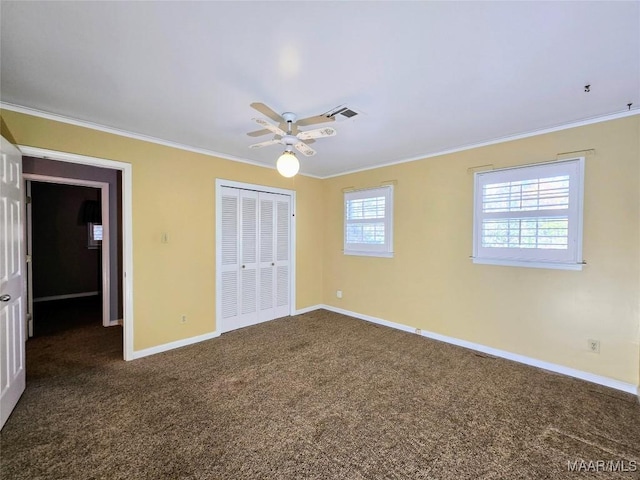 unfurnished bedroom with ceiling fan, dark carpet, crown molding, and a closet