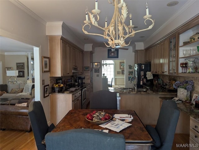 dining space with light hardwood / wood-style floors, an inviting chandelier, crown molding, and sink