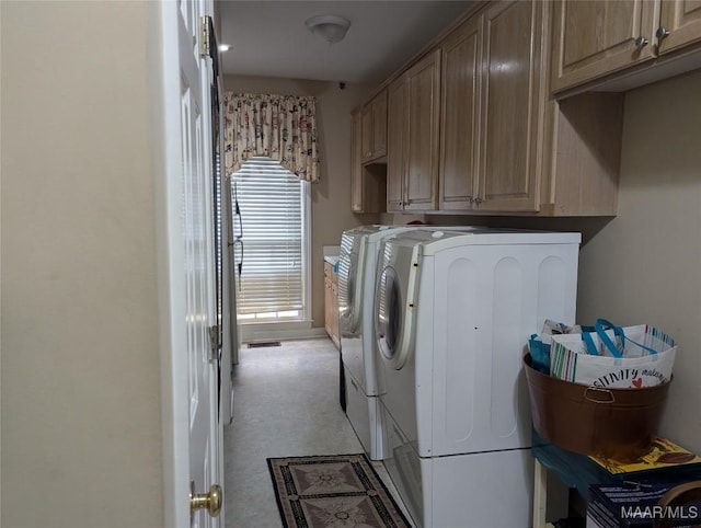 clothes washing area featuring washing machine and dryer and cabinets