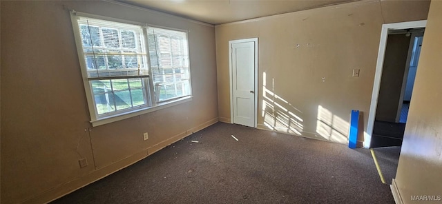 unfurnished room featuring plenty of natural light and dark carpet