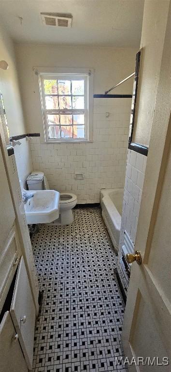 bathroom with sink, toilet, and tile walls