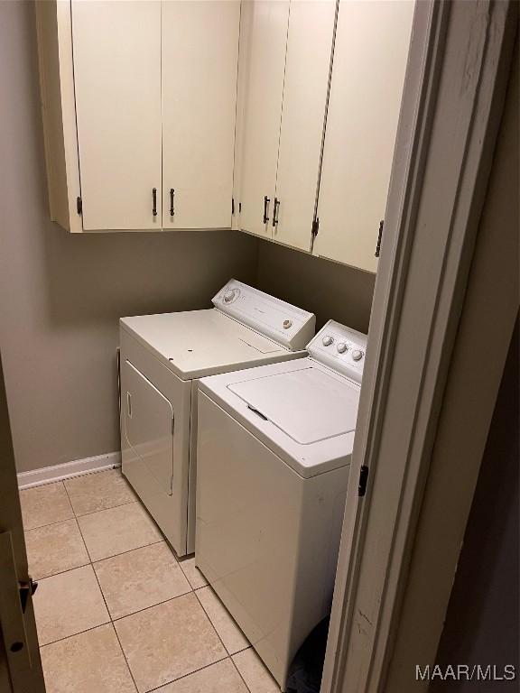 laundry area featuring cabinets, light tile patterned floors, and washing machine and clothes dryer