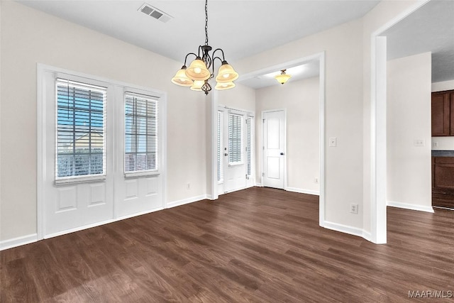 unfurnished dining area featuring dark wood-type flooring and a notable chandelier