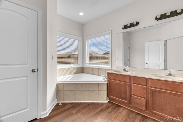 bathroom with tiled tub, hardwood / wood-style floors, and vanity