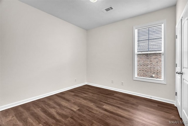 unfurnished room featuring dark wood-type flooring and a healthy amount of sunlight