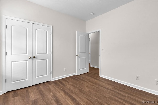 unfurnished bedroom with dark hardwood / wood-style floors and a closet