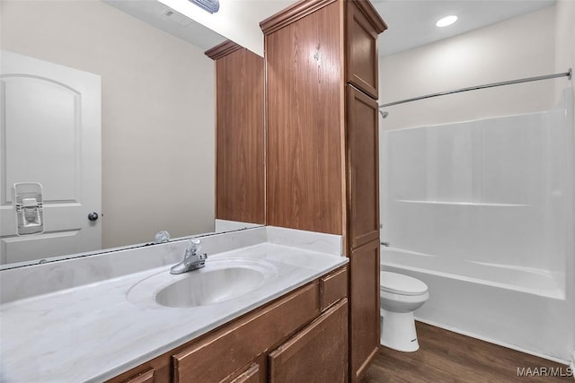 full bathroom with hardwood / wood-style floors, vanity,  shower combination, and toilet