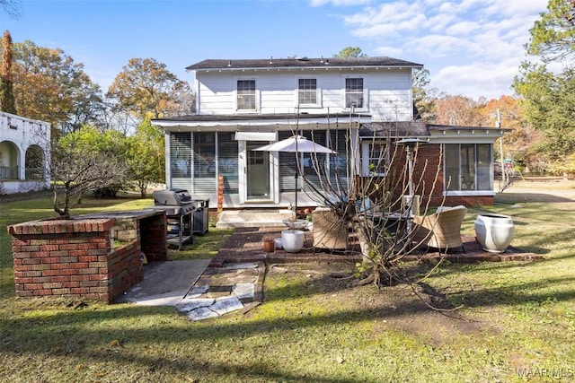 rear view of house featuring a lawn and a sunroom