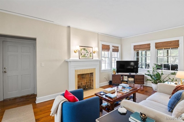 living room featuring hardwood / wood-style floors, ornamental molding, and a tile fireplace