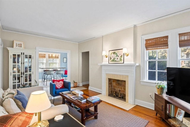 living room with hardwood / wood-style floors, crown molding, and a tile fireplace