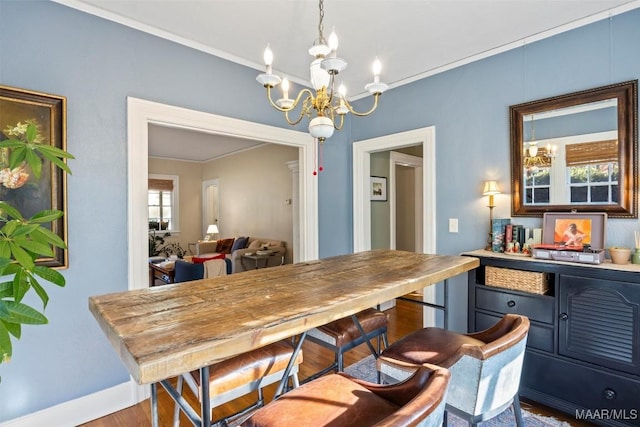 dining area with hardwood / wood-style flooring, ornamental molding, and an inviting chandelier