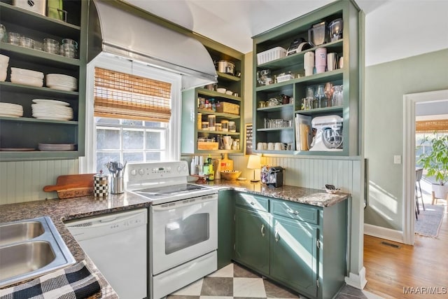 kitchen with dark stone counters, white appliances, sink, green cabinetry, and light hardwood / wood-style floors