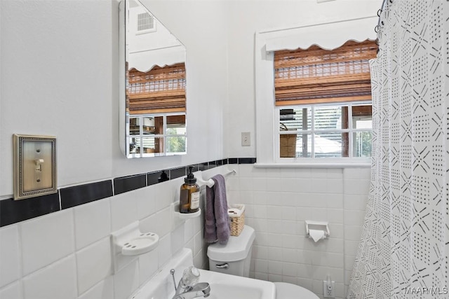 bathroom with a shower with curtain, a wealth of natural light, tile walls, and toilet