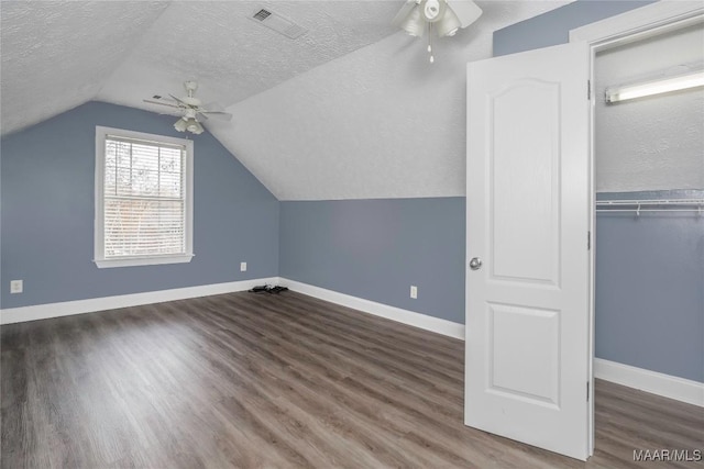 bonus room with dark wood-type flooring and a textured ceiling