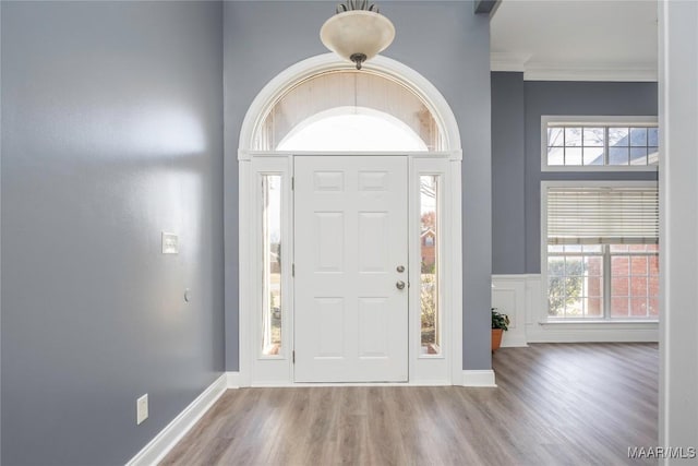 foyer entrance with wood-type flooring and crown molding