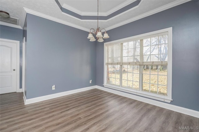 spare room with wood-type flooring, a tray ceiling, an inviting chandelier, and crown molding