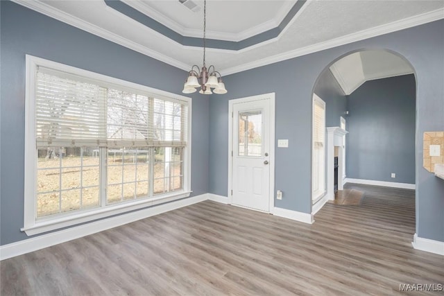 interior space featuring hardwood / wood-style floors, crown molding, a tray ceiling, and a chandelier