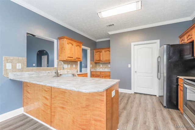 kitchen with sink, ornamental molding, light wood-type flooring, tasteful backsplash, and kitchen peninsula