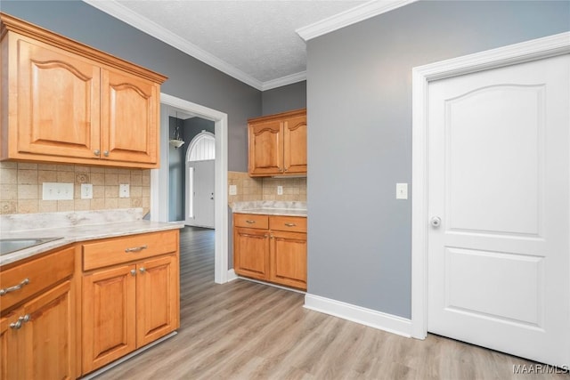 kitchen with a textured ceiling, decorative backsplash, light wood-type flooring, and ornamental molding