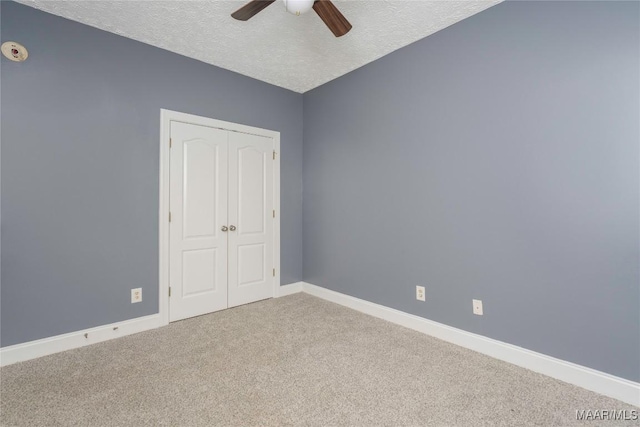 unfurnished bedroom with carpet flooring, ceiling fan, a closet, and a textured ceiling