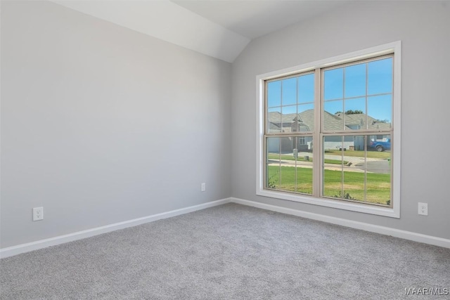 spare room featuring carpet floors, baseboards, and lofted ceiling