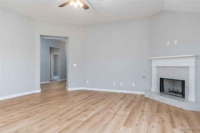 unfurnished living room with baseboards, light wood finished floors, a high end fireplace, and a ceiling fan