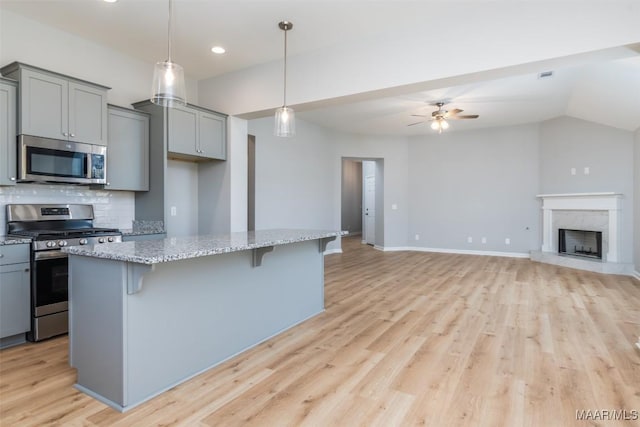 kitchen with a breakfast bar, appliances with stainless steel finishes, and gray cabinets