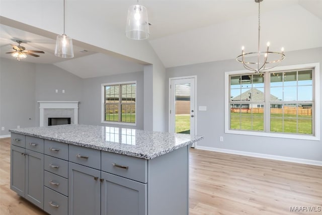 kitchen featuring lofted ceiling, light wood finished floors, a premium fireplace, and gray cabinetry