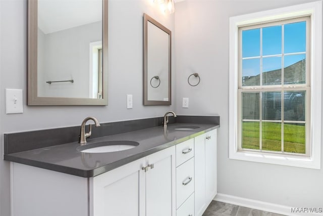 full bath featuring double vanity, baseboards, and a sink