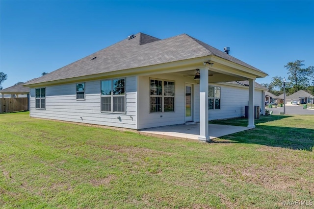 back of house featuring a ceiling fan, a patio, fence, and a lawn