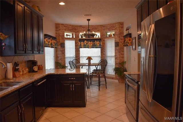 kitchen featuring dark brown cabinets, stainless steel appliances, and brick wall