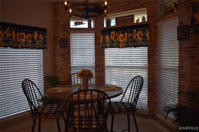 tiled dining area featuring brick wall and a notable chandelier