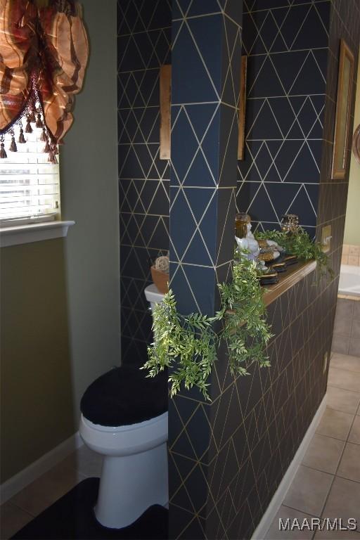 bathroom with toilet, a bath, tile patterned floors, and tile walls