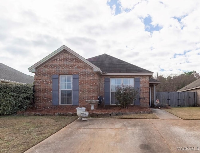 ranch-style house featuring a front lawn, a gate, fence, and brick siding