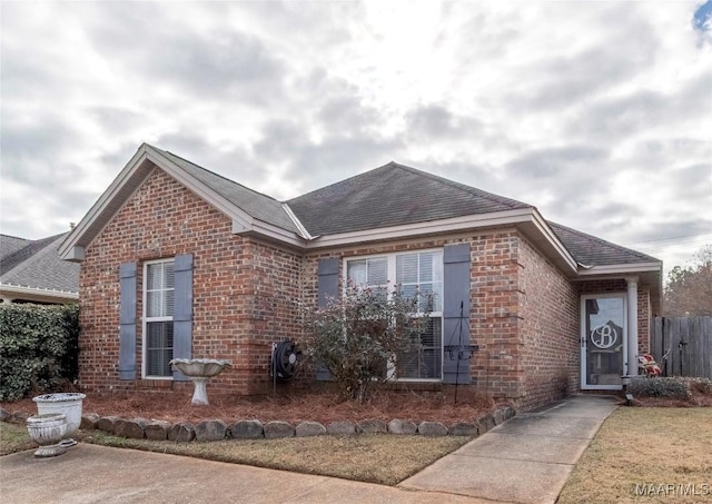 view of front of property featuring brick siding and roof with shingles