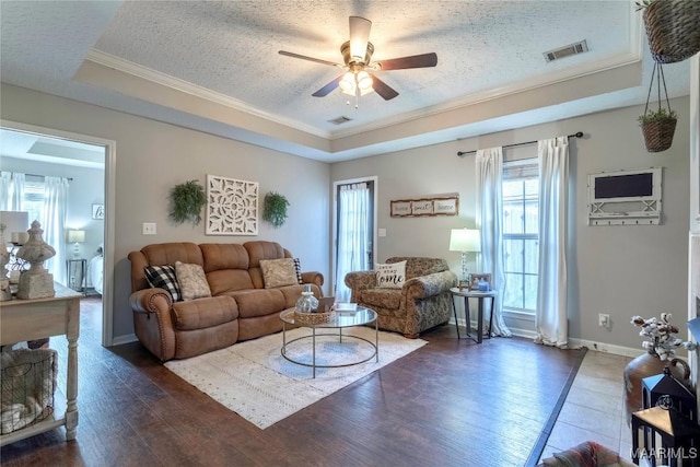 living room with a healthy amount of sunlight, dark hardwood / wood-style flooring, a textured ceiling, and a tray ceiling