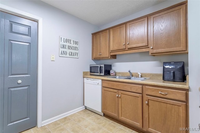 kitchen featuring a textured ceiling, white dishwasher, and sink